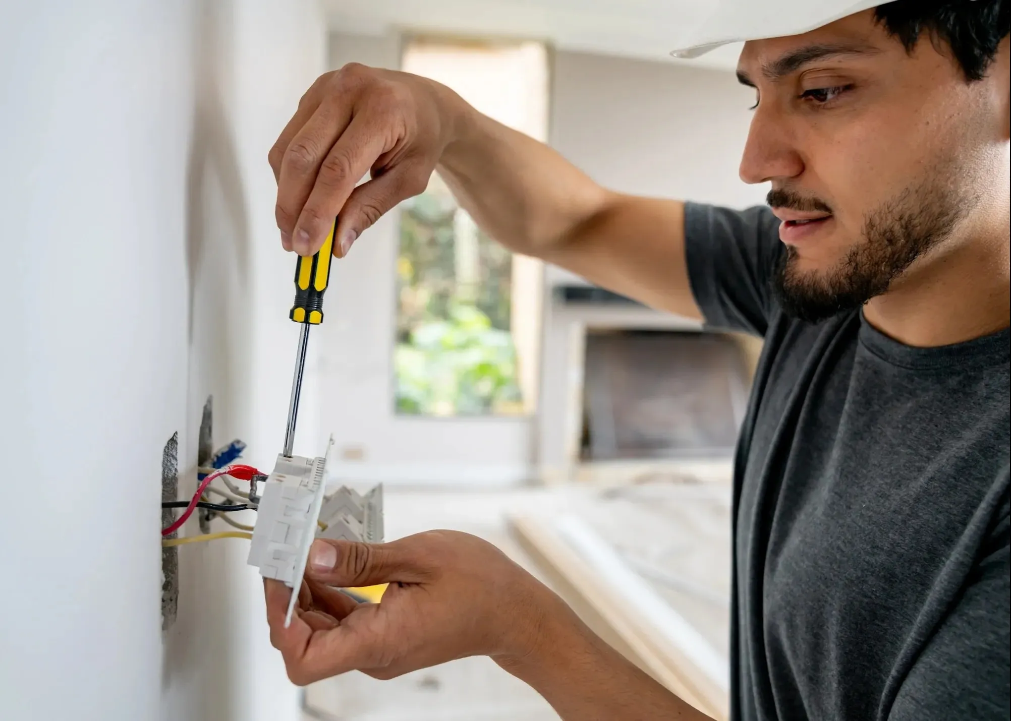 An electrician connecting wires inside a wall switch box